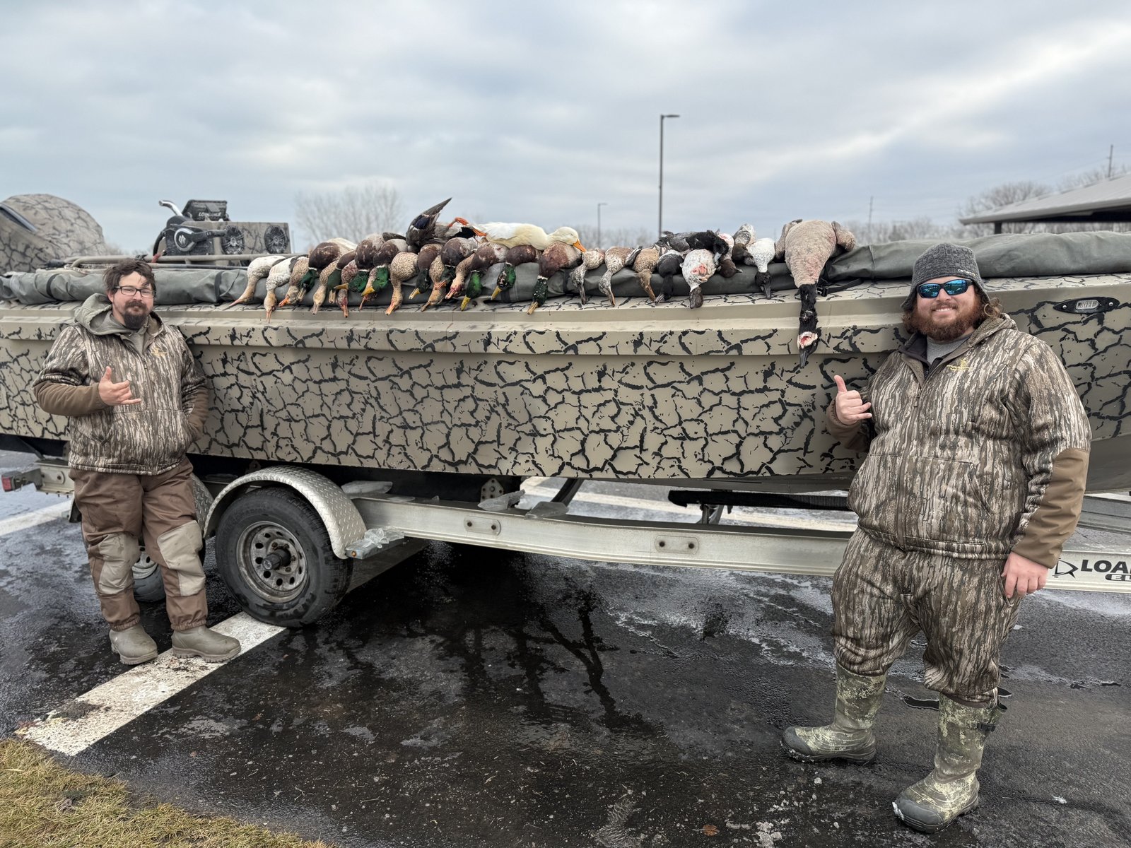 Two Huckeye Charters hunters beside a Lake Erie duck boat loaded with a mixed bag of ducks after a standard waterfowl hunt