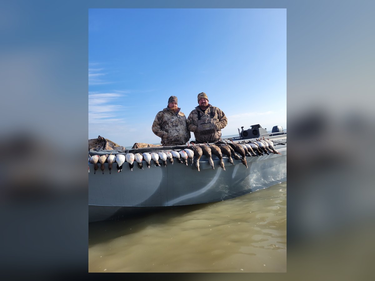 Two hunters with a mixed bag of divers and puddle ducks laid along the boat on Lake Erie