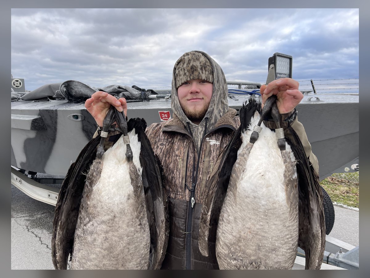 A young hunter holding a pair of banded Canada geese from a Lake Erie goose hunt with Huckeye Charters